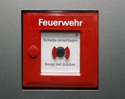 Das Bild zeigt einen klassischen Feuermelder, wie er in öffentlichen Gebäuden und Industrieanlagen zu finden ist. Im Brandfall ermöglicht dieser per Knopfdruck die sofortige Alarmierung der Feuerwehr. Es symbolisiert die Bedeutung von vorbeugendem Brandschutz und schnellen Reaktionsmöglichkeiten im Ernstfall.